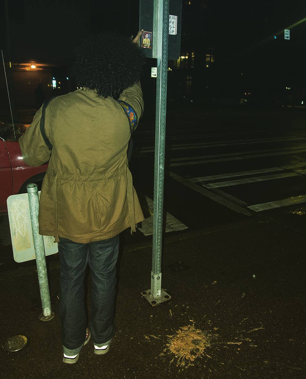 Astral Trap putting up a sticker on a sign with throw up on the ground