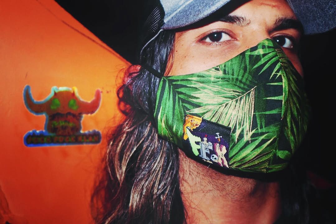 Person wearing a green leaf-patterned face mask with FFK Logo on it