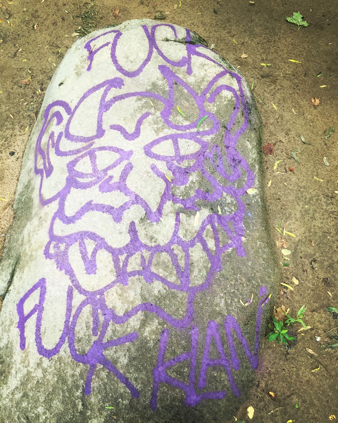 Purple graffiti on a rock with an FFK demon design
